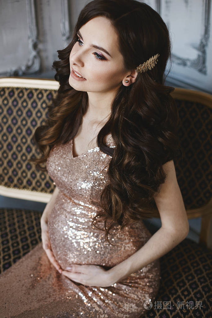一位年轻孕妇身着鲜艳晚礼服的奢华时尚照片怀孕的模特女孩发型别致