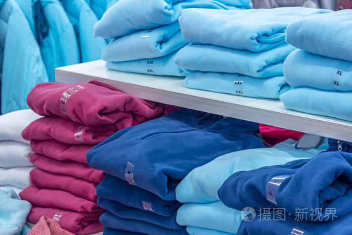 暖和的衣服整齐地叠在架子上一排彩色套头衫