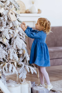 在圣诞树旁拿着圣诞礼物的小女孩