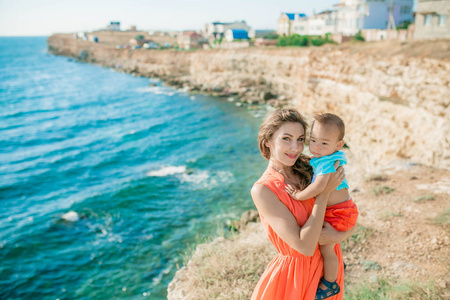 年轻漂亮的妈妈抱着孩子在海边