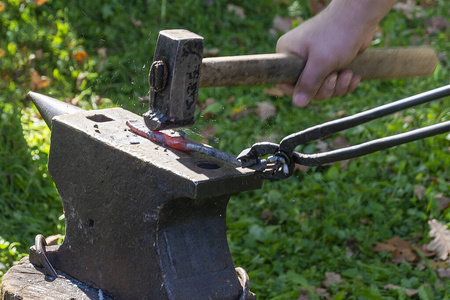 煤锤子铁匠用锤子在铁砧上锻造热金属.体力劳动,手工艺,技能的概念.