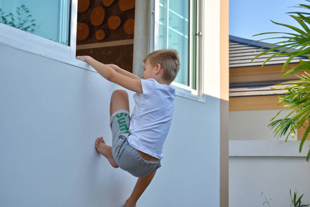 小孩爬墙.男孩爬进一扇开着的窗户.