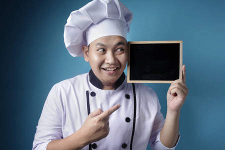 亚洲男厨师展示空黑板，呈现空白字