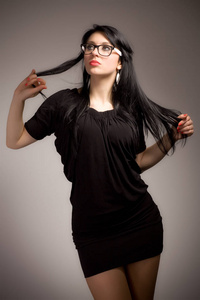 年轻的黑发女人，穿着黑衣服，戴着眼镜
