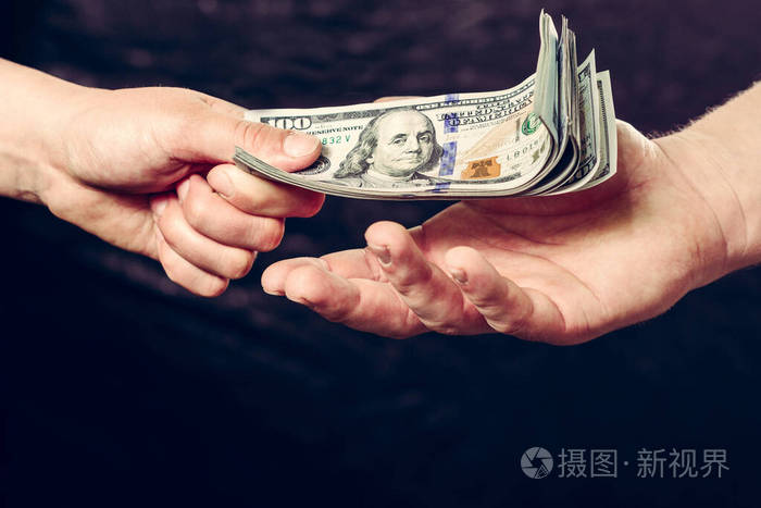 一个商人在黑色背景下握着钱的手的特写镜头