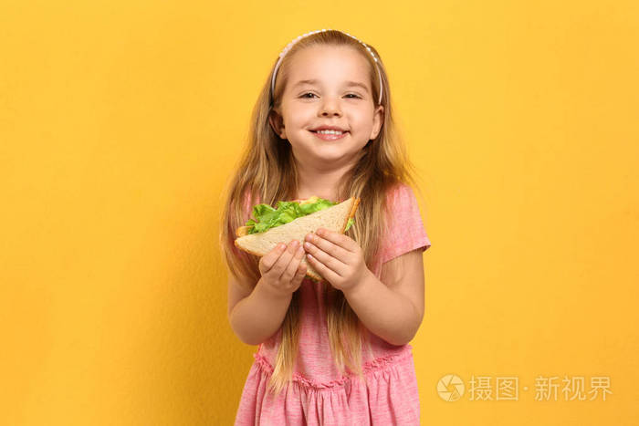 可爱的小女孩黄色背景的美味三明治
