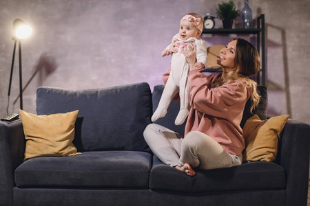 一个女人和她的孩子在舒适的公寓里的沙发上玩耍。妈妈和宝宝都很开心