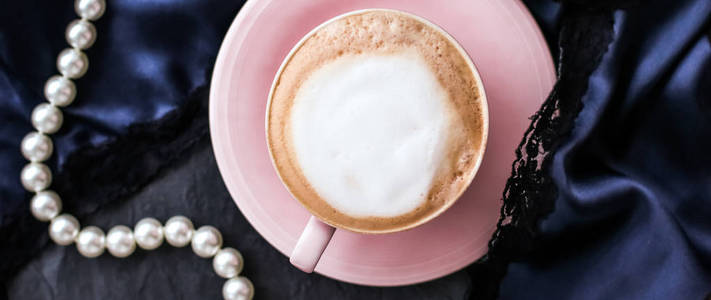 Cup of cappuccino for breakfast with satin and pearls jewellery 