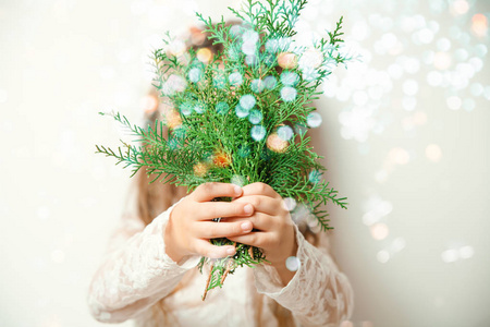 可爱快乐的小女孩在圣诞气氛中笑着拿着云杉树枝的礼品盒和魔法灯
