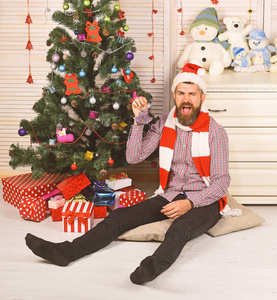 戴着帽子和围巾的家伙躺在圣诞树旁的地板上