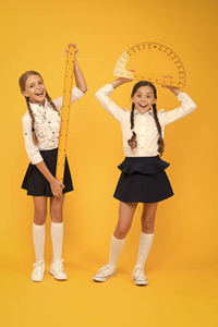 公式。回到学校。数学和几何。穿制服的孩子们在黄墙。友谊和姐妹情谊。快乐的小女孩学习数学。学生使用量角器尺。stem学科