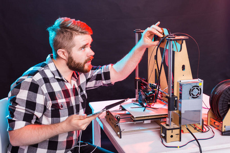 年轻男性设计师工程师，在实验室使用3D打印机，研究产品原型技术和创新理念