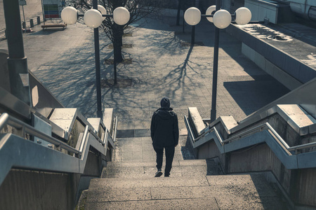 环境楼梯一个穿着黑衣服的年轻人在荒凉的环境中走下楼梯照片