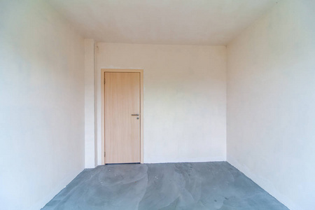 Closed wooden door in empty room, white walls. New empty room un