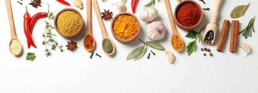 Spoons and bowls with different spices and ingredients on white 