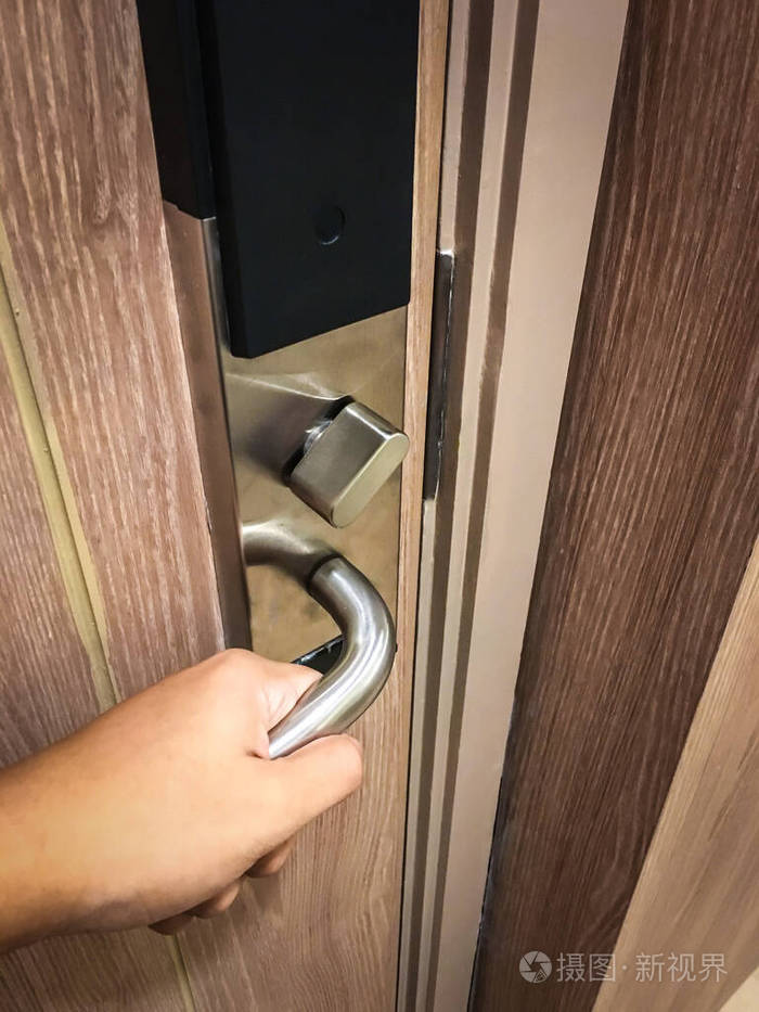 一只手转动铝门把手打开木门