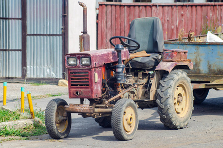 一辆带拖车的老式小型拖拉机停在一条乡村街道上