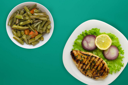  grilled chicken with vegetables lemon, salad, onion on a color