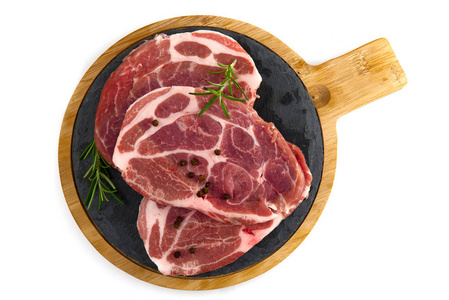 生猪排放在木板上。香料猪肉迷迭香和胡椒。特写生猪排。
