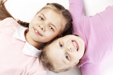 Little smiling girls with pigtails lie nearby. View from above. 