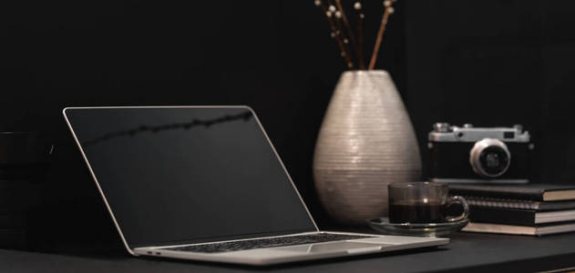 Cropped shot of dark modern designer workplace with open laptop 