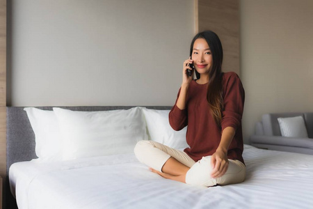 在床上用手机描绘美丽的亚洲年轻女性