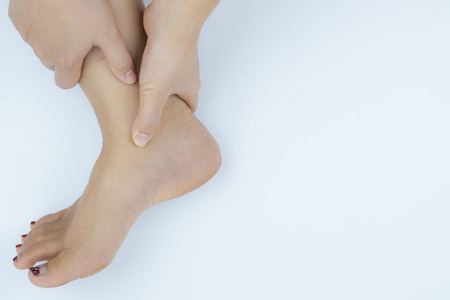 Closeup woman holds ankle pain on white background. Health care 