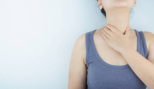 特写:一个女人的手碰到了她喉咙痛的脖子.照片