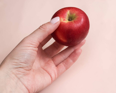 一个女人手拿着一个红苹果，背景柔和