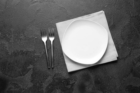 Empty plate and cutlery on dark background