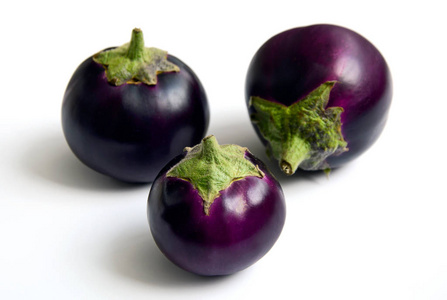 三个圆形的紫色茄子在白色的背景上。