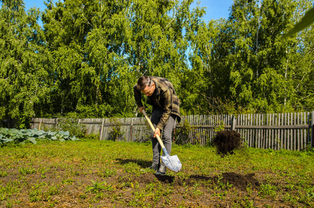年轻人用铲子在花园里挖土