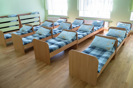 在托儿所学前班的空床上有许多铺着新鲜亚麻布的小床照片