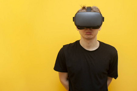 黄色背景下戴着VR眼镜的悲伤的家伙，使用现代虚拟现实设备
