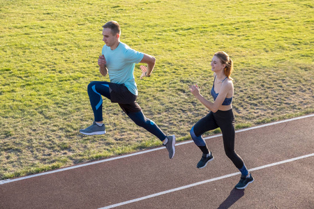 年轻的一对健康的运动员男孩和女孩一边跑一边做运动