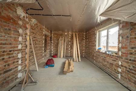 Interior of unfinished brick house with concrete floor and bare 