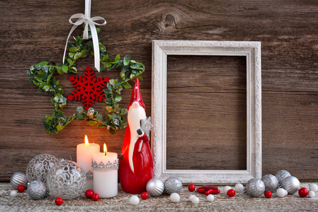 Christmas composition with candles, gnome figurine, photo frame 
