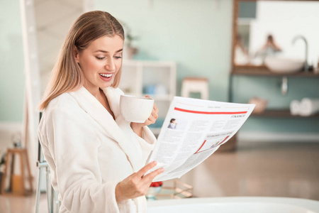 洗茶漂亮的年轻女子在浴室里喝茶看报纸照片