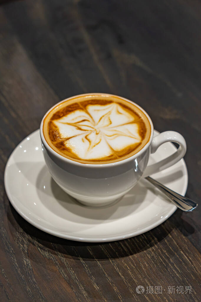 木质背景上美丽的卡布奇诺泡沫牛奶艺术咖啡