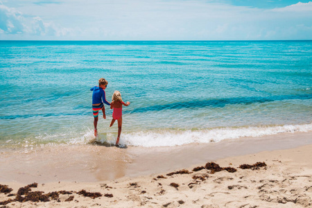 快乐的男孩和女孩在沙滩上跑来跑去玩水