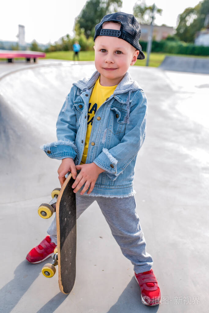 快乐的小男孩3-5岁.快乐的微笑和滑板站在一起.训练学骑滑板.