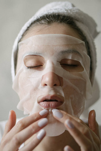 天然美容面膜，防止衰老和面部皱纹。一个穿着毛巾的年轻女人用面膜来滋润面部