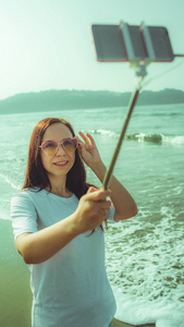 快乐的女人在海边自拍。从上面高兴的女人用