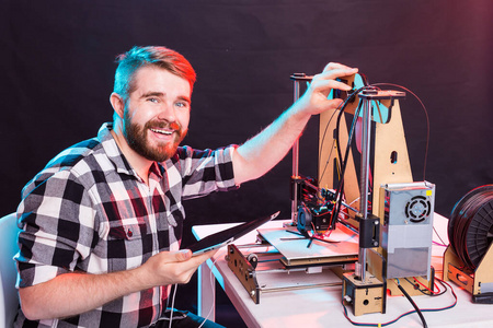 技术与工程概念男工程师晚上在实验室工作，他正在调整一台3D打印机组件。