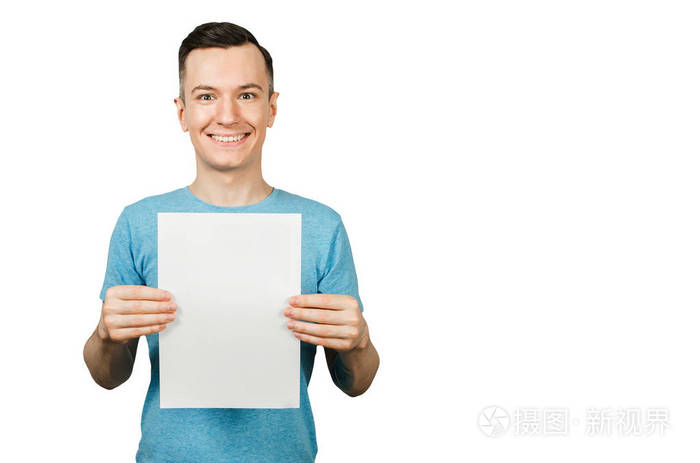 个年轻的微笑着的家伙穿着一件蓝色的t恤手里拿着一张白色背景的a4纸