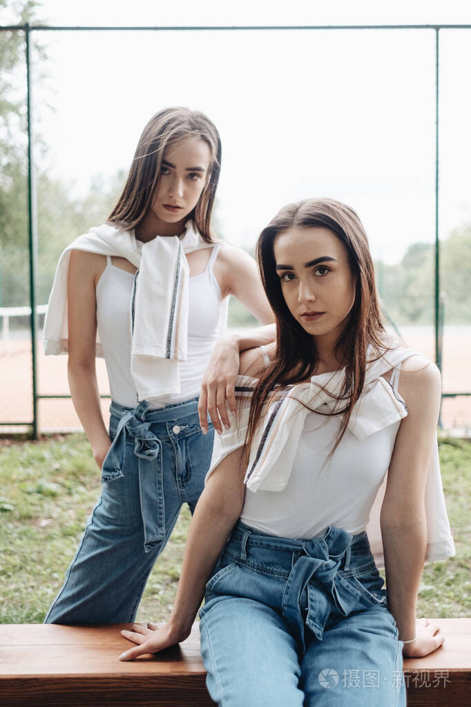 两个年轻的黑发双胞胎姐妹的肖像穿着牛仔裤和白色t恤好朋友永远的