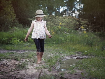 脏的路在泥坑里玩耍的孩子戴帽子光着脚的脏女孩乡村公路照片
