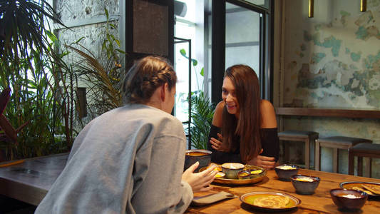 两个女孩在吃午饭时，她们坐在一起，互相依偎着说话