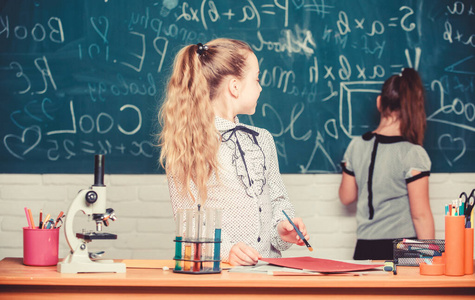 实验室里的小女孩。显微镜。生物课。回到学校。实验室中的科学实验。仔细观察细菌。儿童使用显微镜。小科学家用显微镜工作