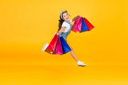 快乐的女孩拿着购物袋跳起来.小孩子拿着纸袋微笑.假期准备和庆祝.